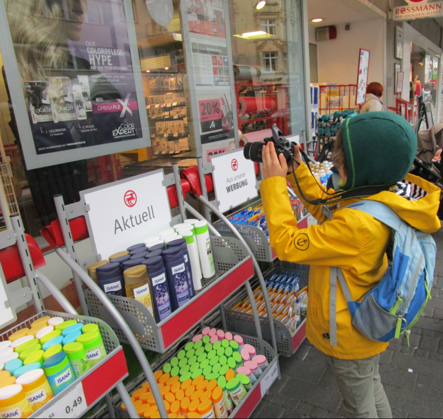 Ein Kind fotografiert Angebotsschilder eines Geschäftes